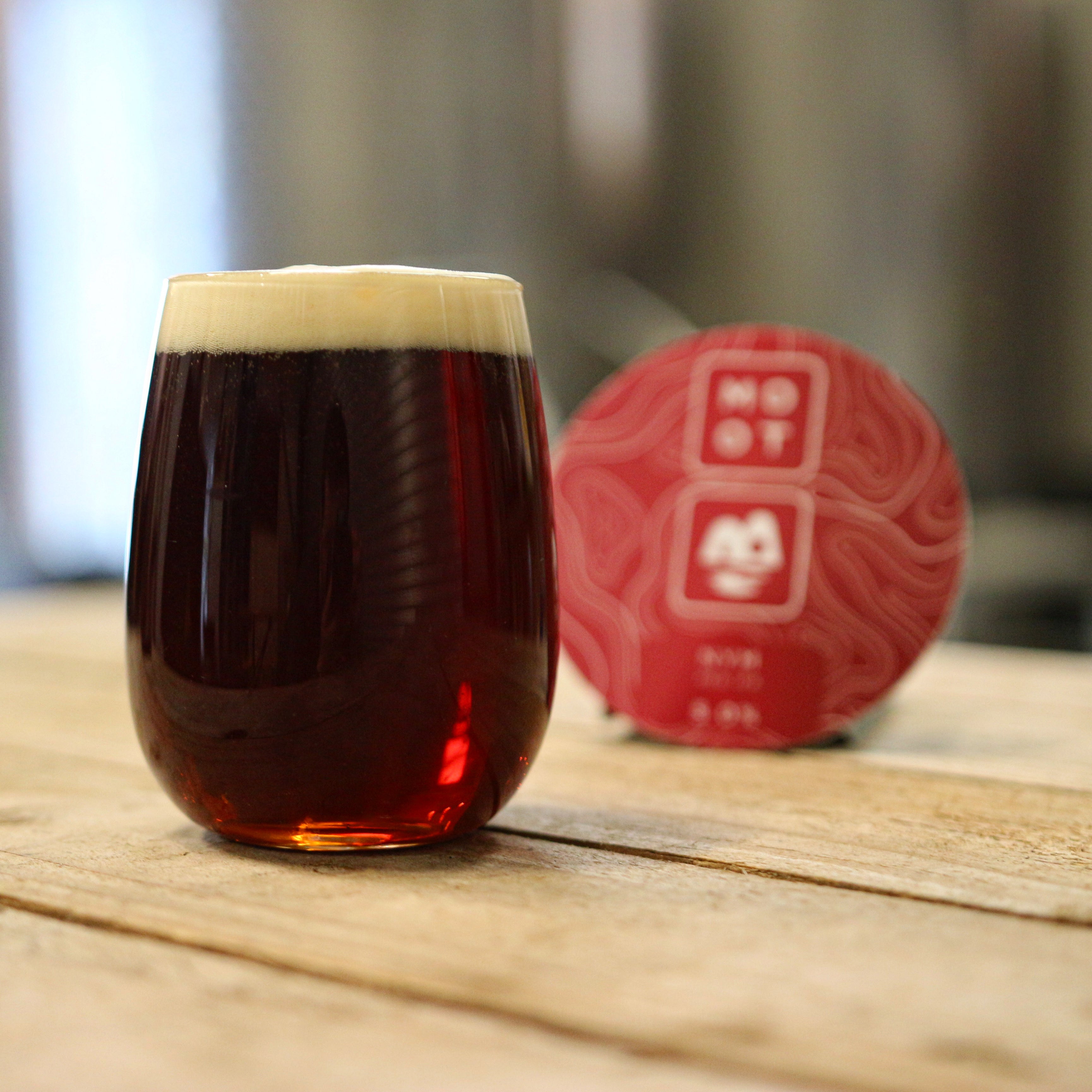 Deep amber-red IPA poured into glass with off-white foam and citrus aroma