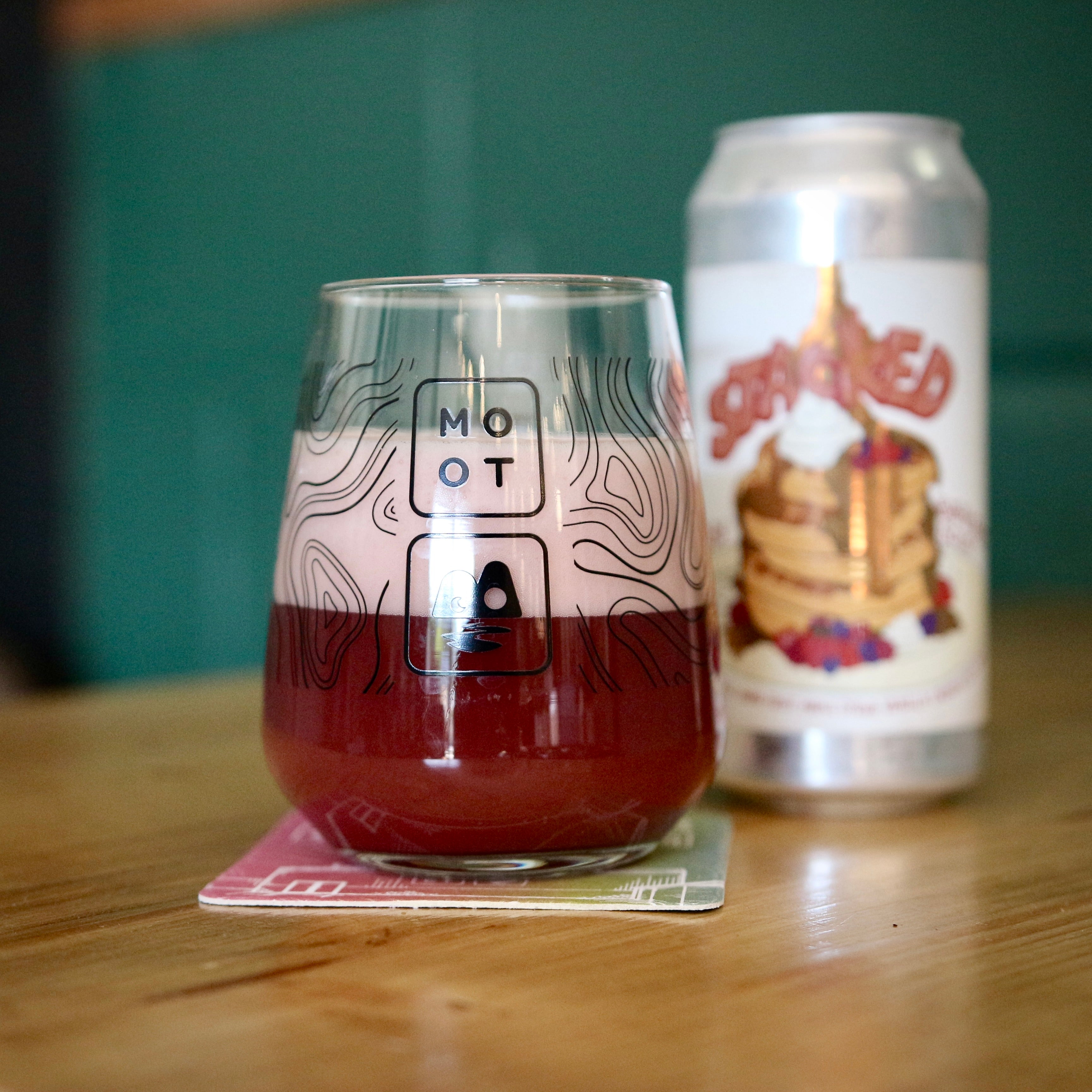 Deep red-purple sour beer poured into glass with creamy foam and berry aroma